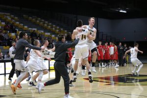 Coaches and players celebrate after the UW Oshkosh men's basketball team defeats River Falls in the WIAC Championship 66-63 on Feb. 28.
