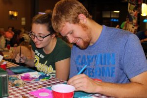 Senior Criminal Justice major Jacob Tennie and Leah Wickland, a senior double majoring in Biology and Art, show off their painting skills at the Painting Class event.