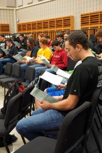 The men’s choir group looks over their sheet music in preparation for their performances. 