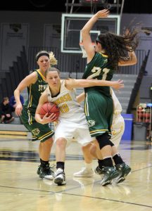 Senior guard Taylor Schmidt (10) fights her way past St. Norbert defenders. The Titans beat the Knights 54-32 at home.