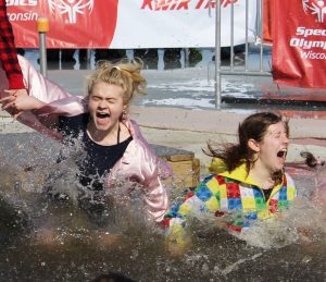 Two friends react to the freezing cold water as they jump into the lake during Saturday’s Plunge event.