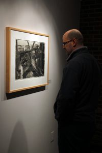 Former UWO student Michael Wartgo admires Kareken’s “Auto Salvage #1.”