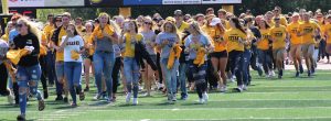 New students storm the field before the football game to welcome the team as part of Titan Takeover.