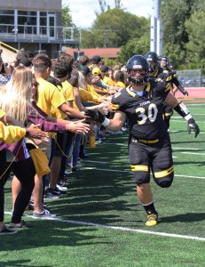 Running back Beau Ash high-fives through a line of fans as he runs on the field to play against Virginia University of Lynchburg.