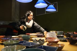 Jessica Martinez peruses bowls that were crafted by the art department for the charity event Empty Bowls.