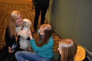 "ABOVE: Liam the therapy dog is all smiles as he helps UWO students forget their stress. LEFT: Two students hug a tiny dog. RIGHT: A student takes a photo of a golden retreiver."