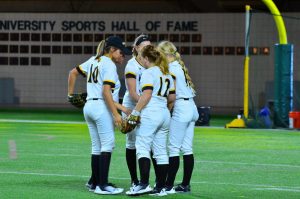 Five UW Oshkosh Titan softball players meet on the field during a pause in the action over the opening weekend in Michigan.