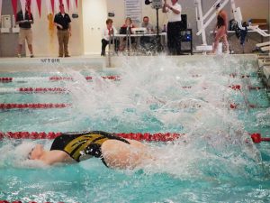 A female UWO swimmer launches into the backstroke.