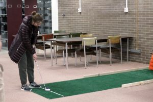 A mini golfer lines up her shot at one of the second-floor holes. The course utilized the library’s multiple floors and furniture to create hazards. 