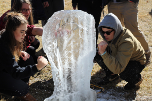 Zeta Tau Alpha and Beta Theta Pi members work to sculpt their ice into a light bulb shape.