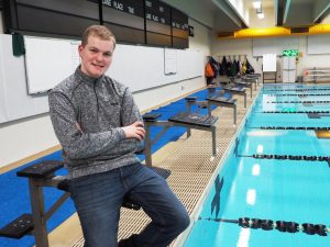High school student Jarod Falk poses on the starting blocks at Albee Pool. Falk uses the pool to train for the Special Olympics USA Games in Seattle, Washington. Members of the men’s team volunteer to practice with Falk on their own time.