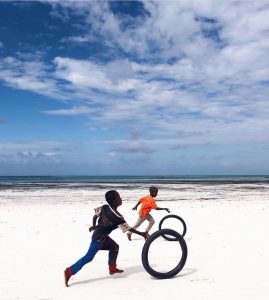 Children race broken bicycle rims on the beach in Zanzibar, Tanzania.