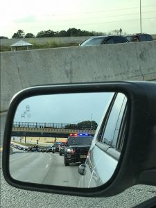 A line of police cars can be seen in the side mirror during rush-hour traffic on I-94 in Milwaukee. The road was shut down to honor a Milwaukee officer killed on duty.