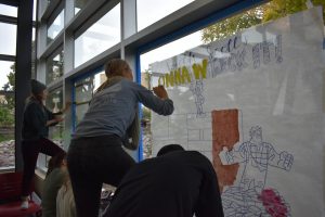 Students paint windows in Reeve Memorial Union during homecoming week. 