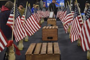 Boots with photos of fallen service members, a ribbon, and an American flag