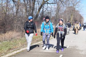 Three students walking down a road with their rucksacks