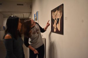 Two students examine art pieces in our on-campus art gallery
