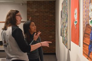 Seniors Rachel Blohowiak and Colleen Montevilla look at the 19th Annual Honors Exhibition pieces.