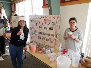 Students pose in front of their poster for UW-Fox Valley’s fifth international student event.