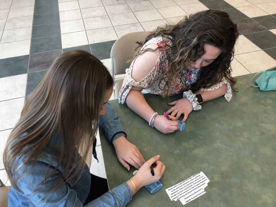 Maddie Nolan and Savanna Peterson write supportive messages for sexual assualt awareness.