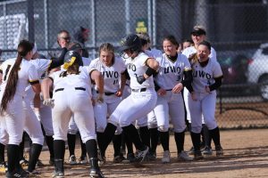 Abby Menting comes to homeplate, surrounded by teammates