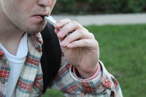 A UWO student takes a drag on a Juul e-cigarette while walking to campus.