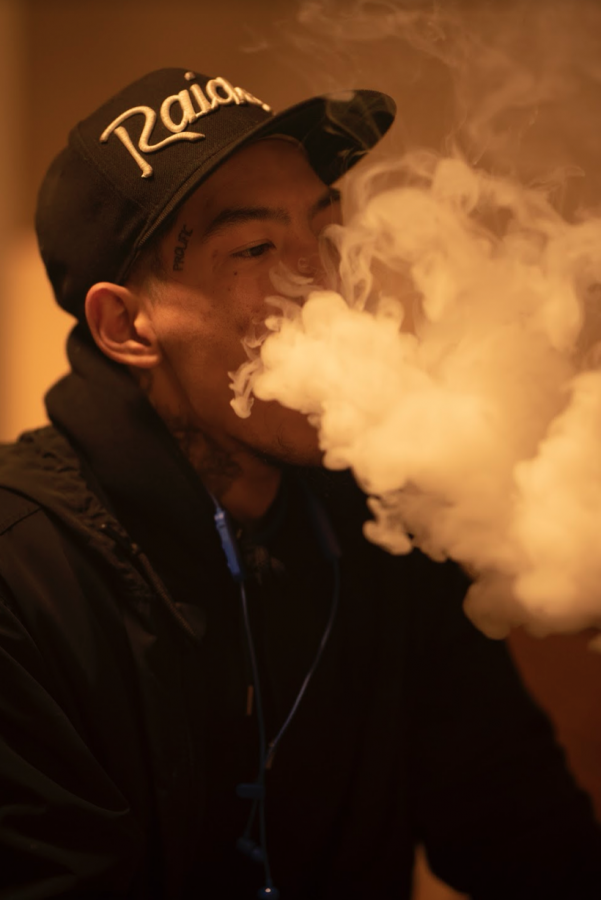 Alex Mangmoradeth exhales a cloud of vapor. Researchers found that when e-cigarette taxes increase by 10%, sales of vaping devices decrease by 26% and traditional cigarette sales rise by 11%. 