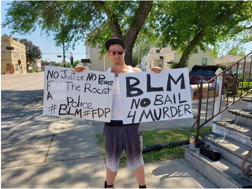 Kaitlyn Scoville / The Advance-Titan — Christian Leiske holding up two of his signs as he protests outside his home.
