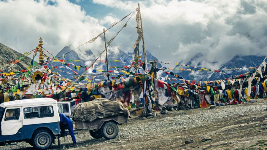 Mountain peaks, glaciers, and prayer flags near the Kunzum La Pass, a high mountain pass connecting the Lahaul and Spiti valleys in the Indian Himalaya. 
