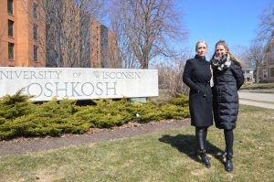 Loschen, left, and Bachmann at the UWO sign on campus. The two depart for Germany on Friday.