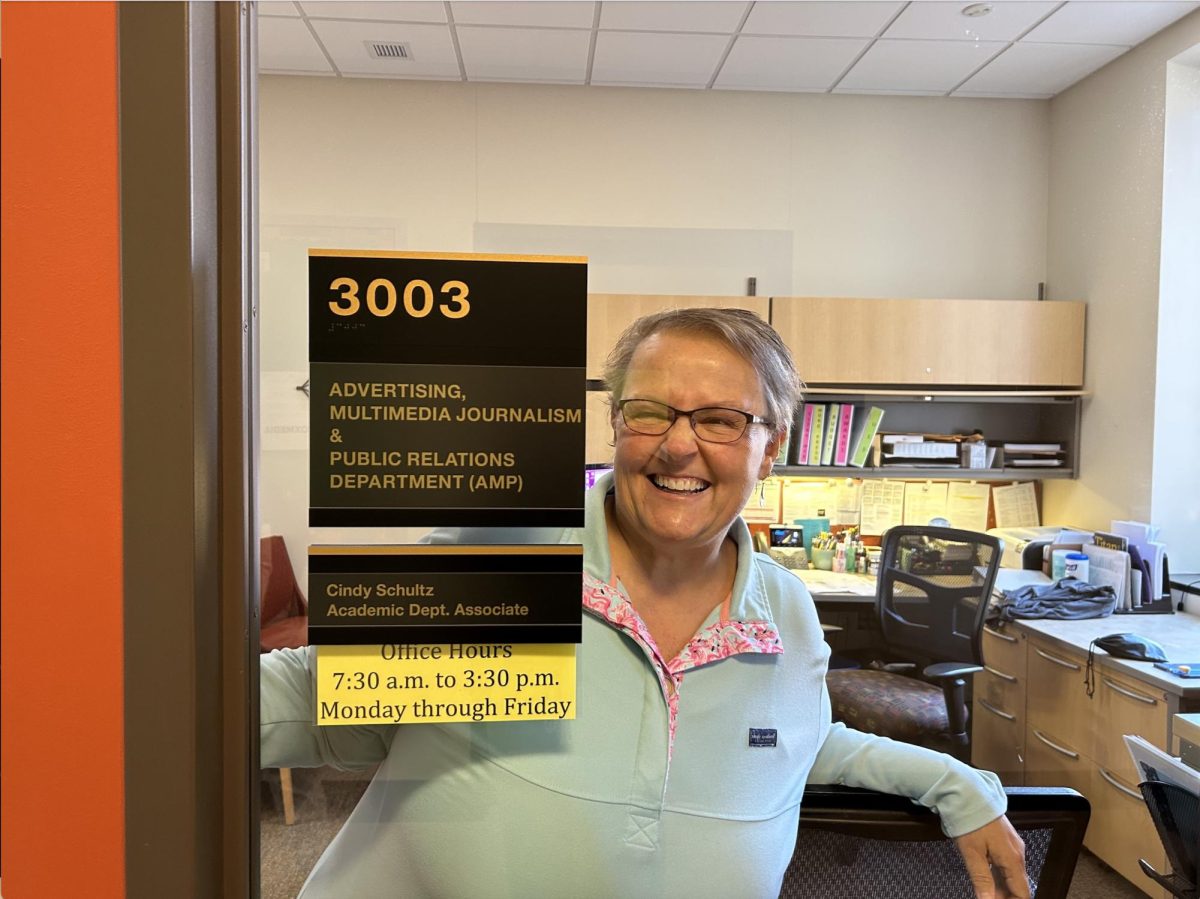 Cindy Schultz, the academic department associate for AMP, smiles watching students pass her office in Sage Hall. She has been a UWO Classified Staff for over 31 years