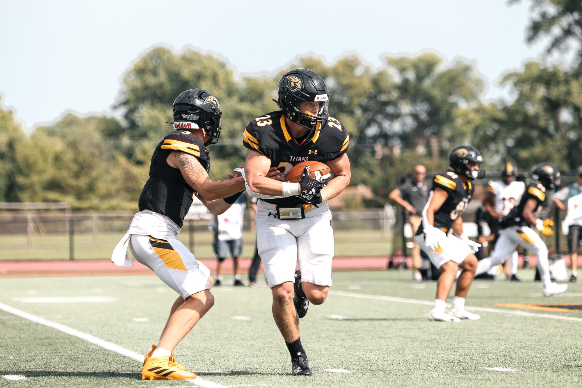Morgan Feltz / The Advance Titan // Quarterback Kobe Berghammer hands the ball off to Doug Berson (23) in Oshkosh’s home opener against Texas Lutheran University.
