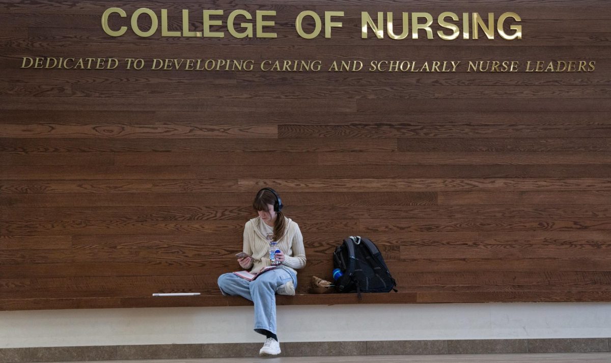 Courtesy of UWO Flickr A student sits below the College of Nursing sign in the Clow Academic Complex.