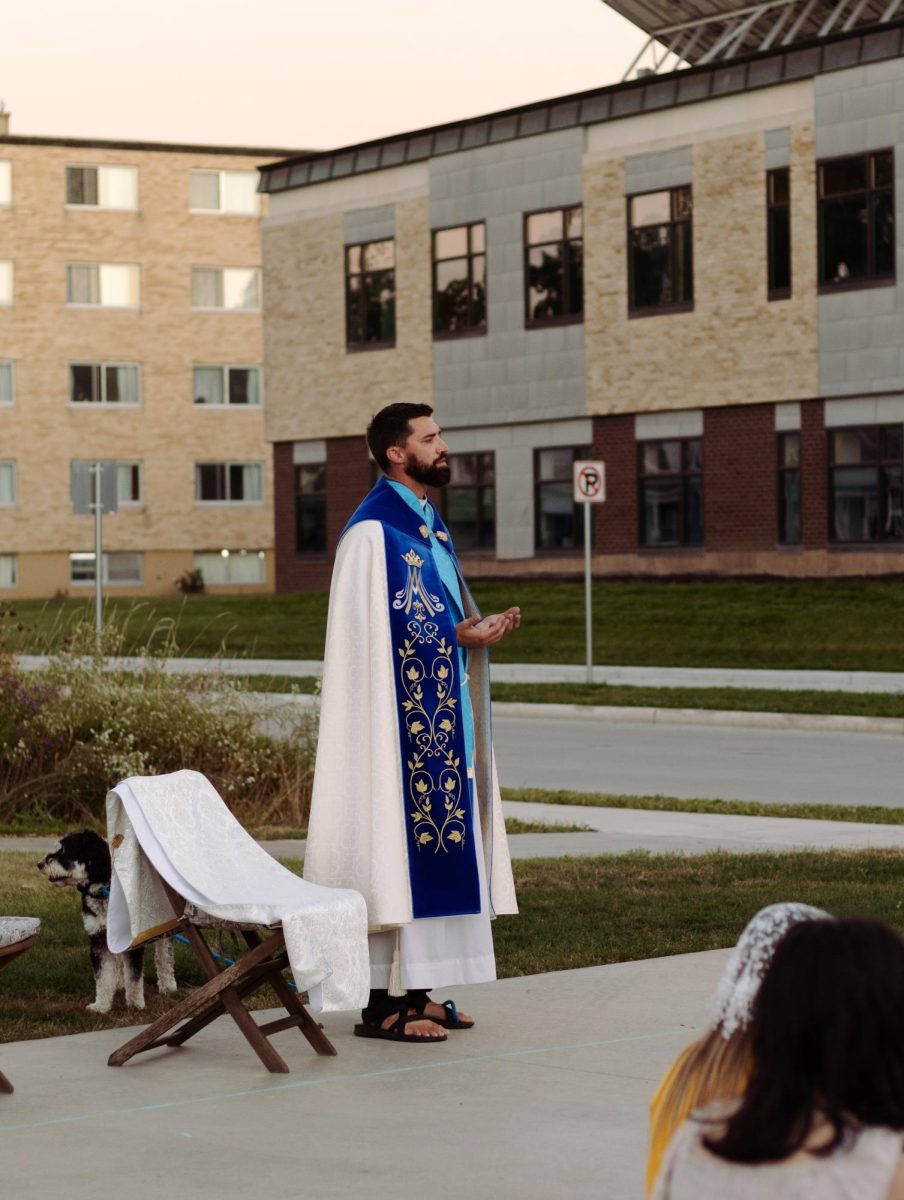 Fr. Zach Weber leads a procession of students during the Eucharistic Procession on Friday.