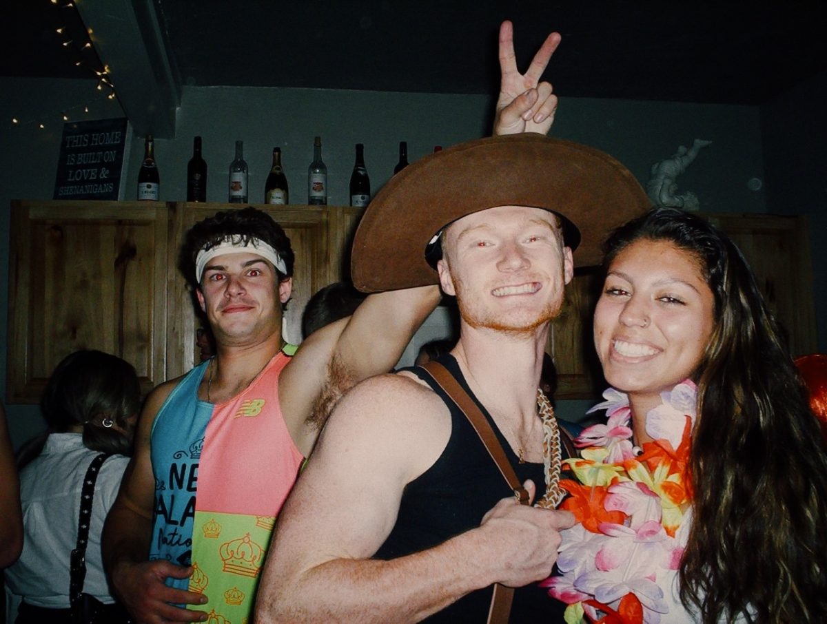 Two UW Oshkosh students having fun and smiling for a photo get photobombed at one of UWOs infamous house parties.