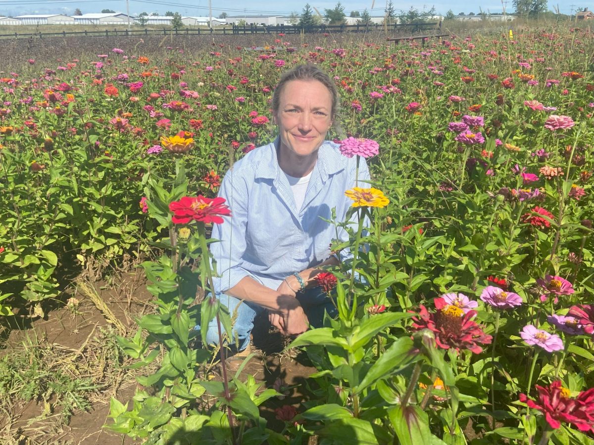 Cassidy Johnson / Advance-Titan – Co-owner of The Bloomtique in Oshkosh, Gena Tigert, crouches in a colorful field of zinnias at one of The Bloomtique’s many flower fields.
