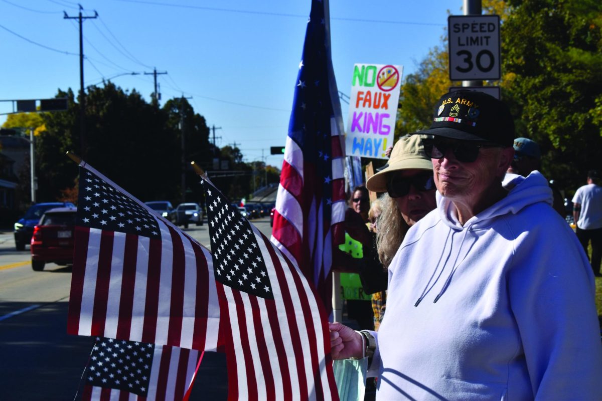 Josh Lehner / Advance-Titan – Protesters hold American flags and signs out toward cars passing along Congress Avenue during the “No Kings” protest Oct. 18 in downtown Oshkosh.