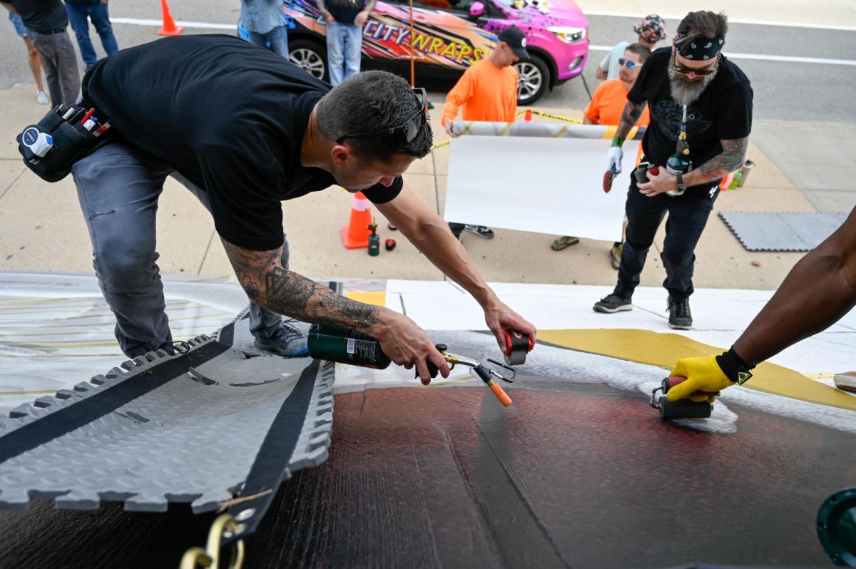 Jess Duch / Advance-Titan -- Crews from Art City Wraps install a new mural on the side of the Kolf Sports Center.