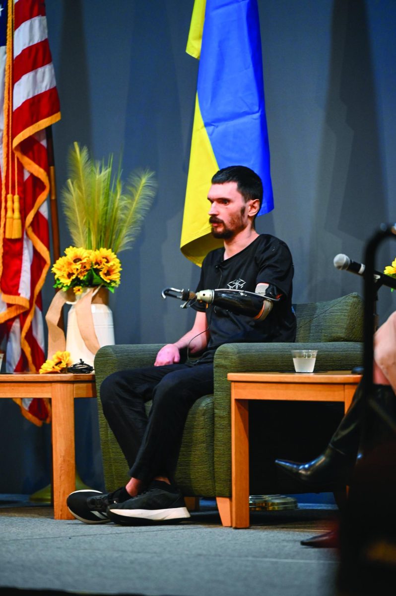 Jess Duch / Advance-Titan – (Left) Davyd Piasetskyi, a Ukrainian veteran and drone operator, speaks about drone warfare in Ukraine at the event in Reeve Union Ballroom last Wednesday, Sept. 24. (Right) UWO student Sabrina Hanson holds a destroyed fragment of a Russian Shahed drone as part of the exhibit "Dronesv - The Game Changers of the War in Ukraine."